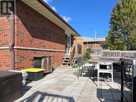 A patio with a table and chairs is in front of a brick building.