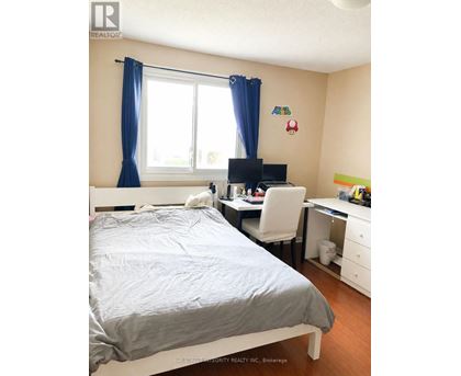 A bedroom with a bed, desk, and chair.