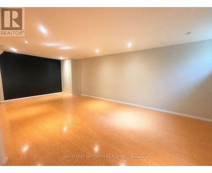 A room with wooden flooring and a logo of Bay Street Integrity Realty Inc. Brokerage on the wall.