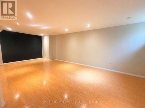A room with wooden flooring and a logo of Bay Street Integrity Realty Inc. Brokerage on the wall.