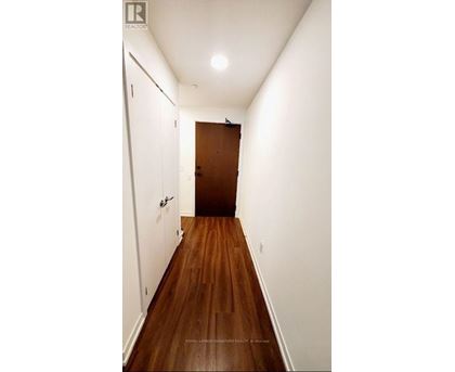 A long hallway with a brown door at the end.
