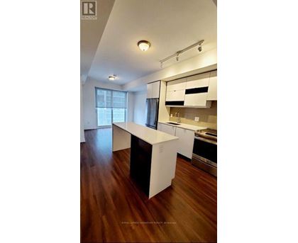 A modern kitchen with white cabinets and a wooden floor.