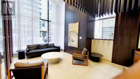 A living room with a couch, chair, and a painting on the wall.