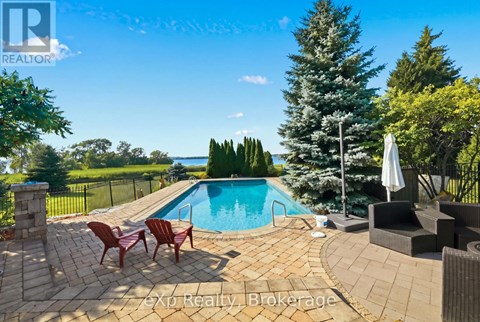 A pool surrounded by a patio and chairs.