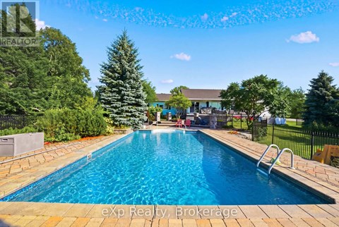 A pool surrounded by trees and a house in the background.
