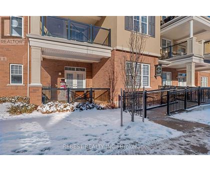 A snow-covered front yard of a brick building with a black fence.