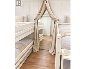 A white bunk bed with a canopy and a striped pillow.