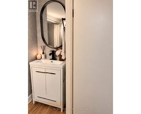 A white bathroom vanity with a round mirror above it.