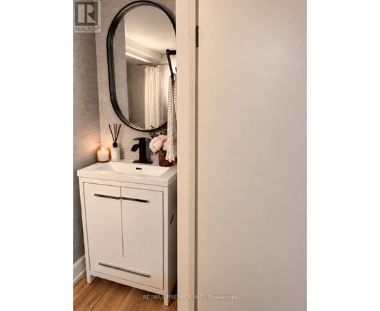 A white bathroom vanity with a round mirror above it.