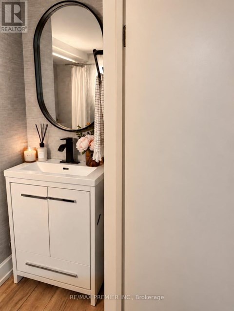 A white bathroom vanity with a round mirror above it.