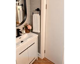A white bathroom with a sink, mirror, and towel rack.