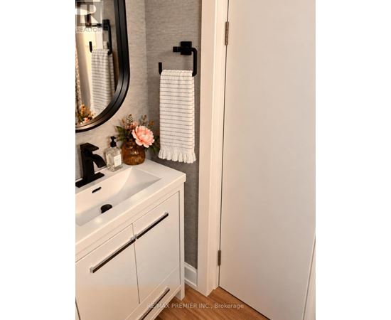 A white bathroom with a sink, mirror, and towel rack.