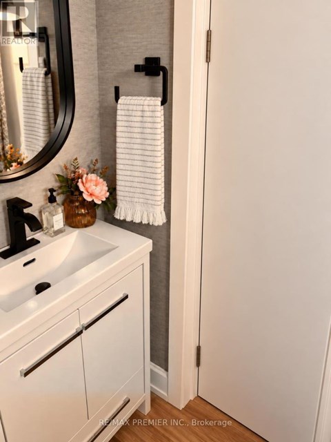 A white bathroom with a sink, mirror, and towel rack.
