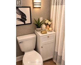 A white toilet sits next to a white cabinet with a plant on top.