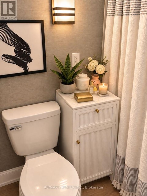 A white toilet sits next to a white cabinet with a plant on top.