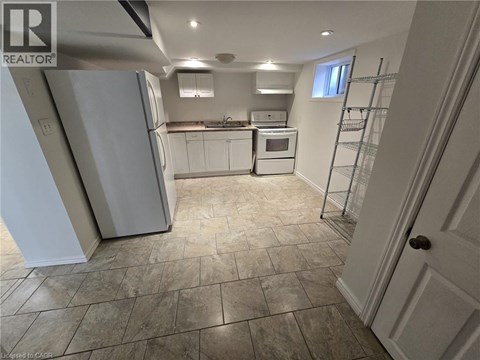 A kitchen with white appliances and a tiled floor.