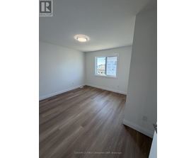A room with wooden flooring and a window showing a view of a building.
