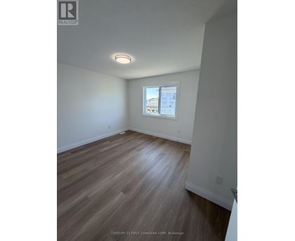 A room with wooden flooring and a window showing a view of a building.