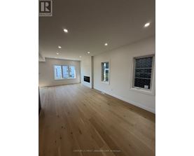 A spacious room with wooden flooring and a large window.