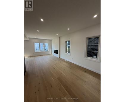 A spacious room with wooden flooring and a large window.
