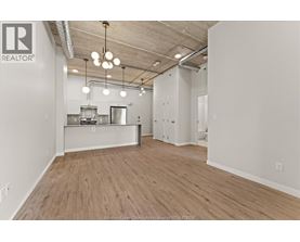 A spacious office with wood flooring and a kitchenette.