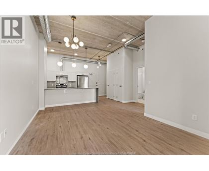 A spacious office with wood flooring and a kitchenette.