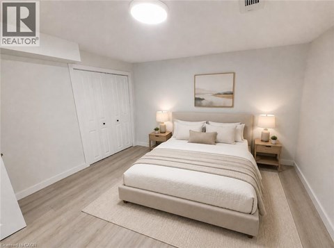 A bedroom with a large bed, two nightstands, and a painting on the wall.