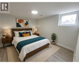 A bedroom with a bed, two lamps, a plant, and a painting on the wall.