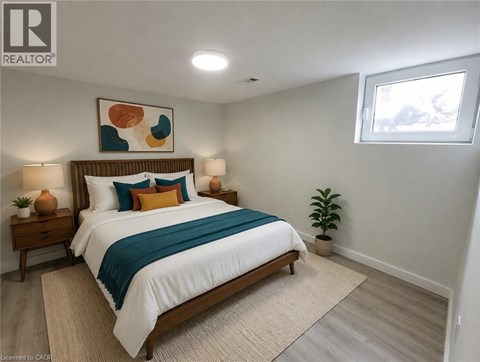 A bedroom with a bed, two lamps, a plant, and a painting on the wall.