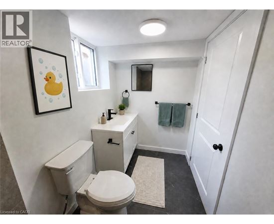A bathroom with a toilet, sink, and mirror.