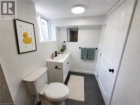 A bathroom with a toilet, sink, and mirror.