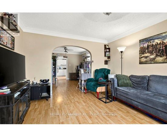 A living room with a grey couch, a green chair, and a painting on the wall.