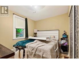 A bedroom with a bed, nightstand, and a window with a view of a garden outside.
