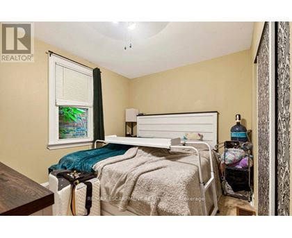 A bedroom with a bed, nightstand, and a window with a view of a garden outside.