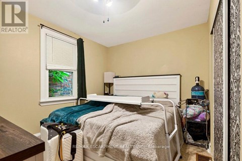 A bedroom with a bed, nightstand, and a window with a view of a garden outside.