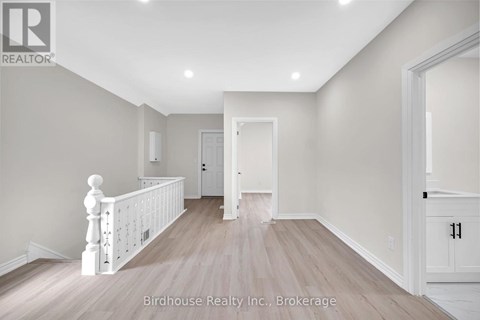 A spacious room with light wood flooring and white walls.