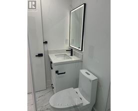 A white bathroom with a toilet, sink, and mirror.