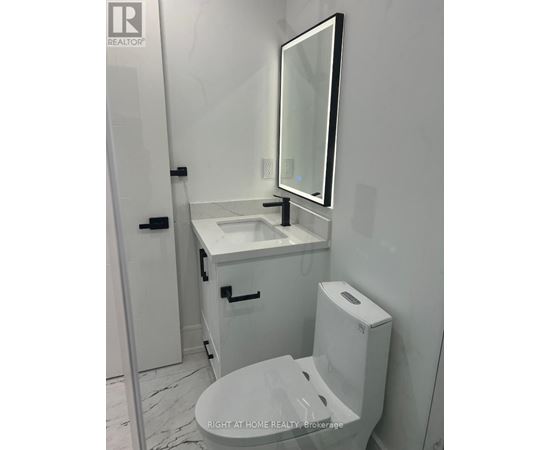 A white bathroom with a toilet, sink, and mirror.