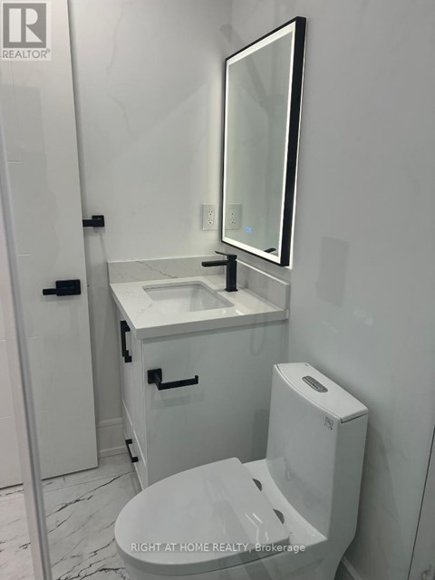 A white bathroom with a toilet, sink, and mirror.
