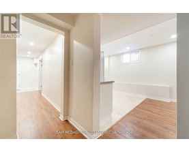 A realtor photo of a spacious empty room with wood flooring and white walls.