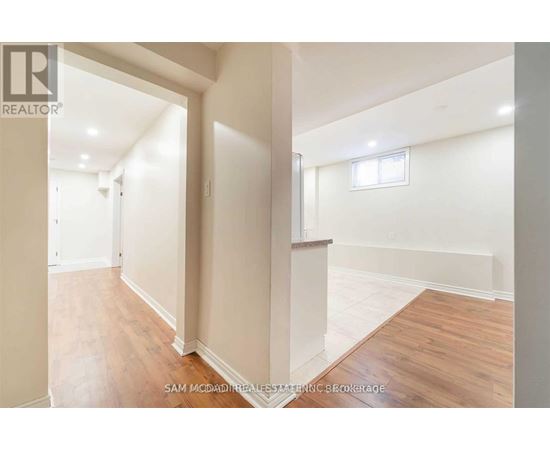 A realtor photo of a spacious empty room with wood flooring and white walls.
