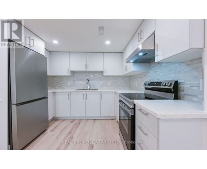 A modern kitchen with white cabinets and a stainless steel refrigerator.