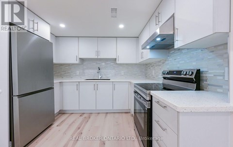 A modern kitchen with white cabinets and a stainless steel refrigerator.