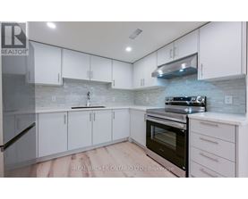 A kitchen with white cabinets and a stone backsplash.