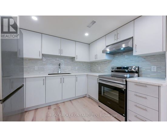 A kitchen with white cabinets and a stone backsplash.