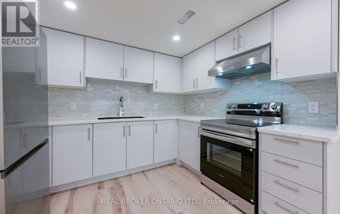 A kitchen with white cabinets and a stone backsplash.