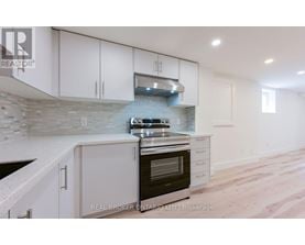 A modern kitchen with white cabinets and a stone backsplash.