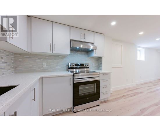A modern kitchen with white cabinets and a stone backsplash.