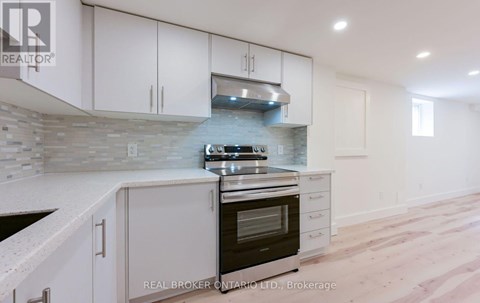 A modern kitchen with white cabinets and a stone backsplash.