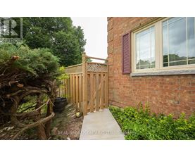 A wooden fence and gate in front of a brick building.